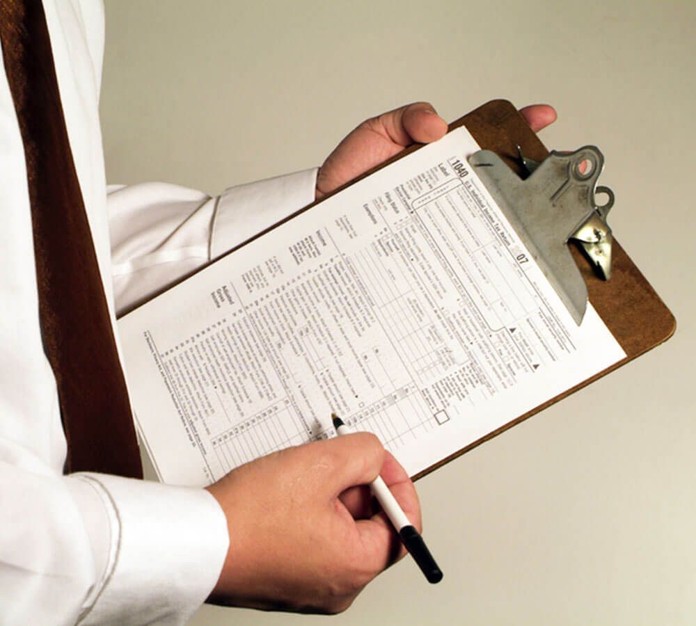 A man holding a clipboard with tax paperwork on it