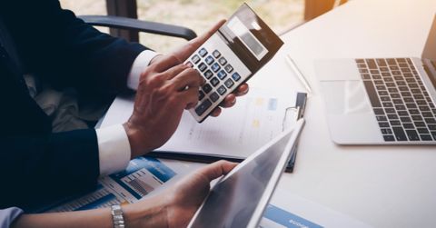 A man with a calculator in his hands at his desk