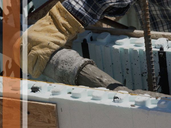 A close up of a construction worker laying concrete inside of a form