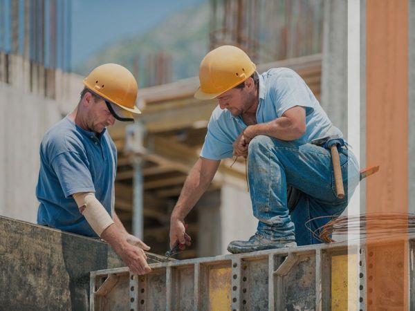 Two construction workers adjusting a concrete form