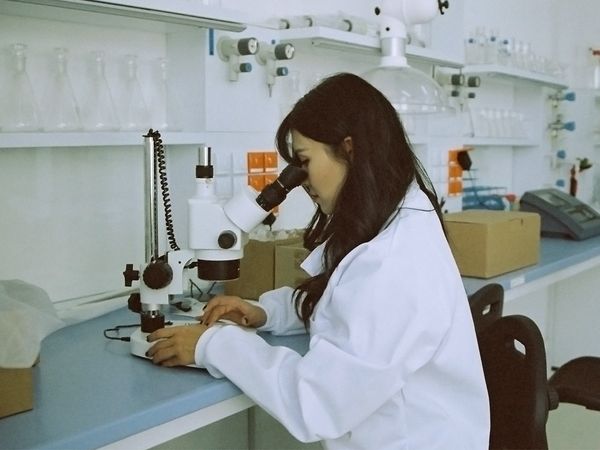 Woman using a microscope to perform diagnostic testing