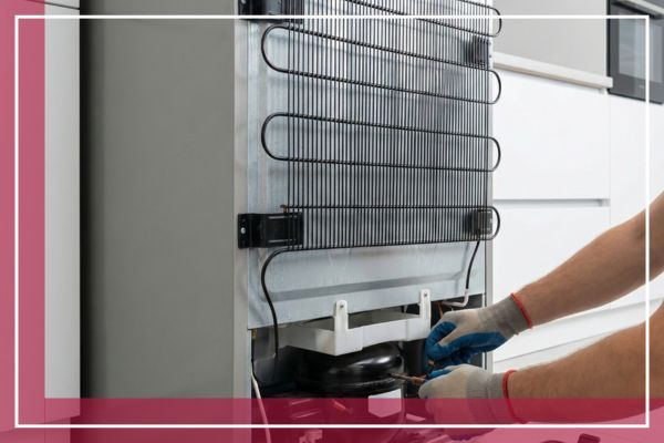 Technician repairing the compressor coils at the back of a refrigerator.