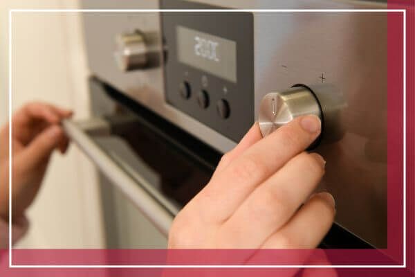 person adjusting temperature on oven