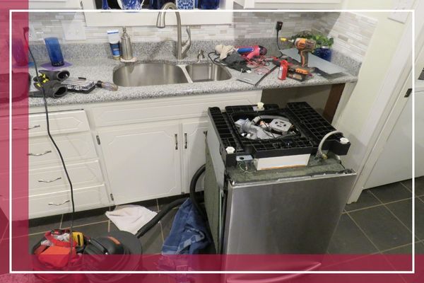 A dishwasher pulled out from under the counter in a kitchen, with tools and parts scattered around, indicating a repair in progress Locust Valley 1.jpg
