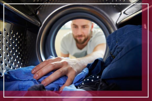 A view from inside a washing machine drum, looking out at a man with a beard reaching in to unload blue laundry Locust Valley 2.jpg