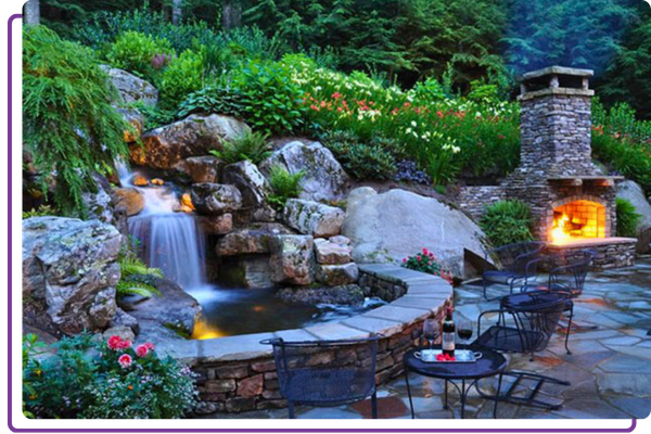 a stone-surrounded water feature and a stone fireplace on a patio