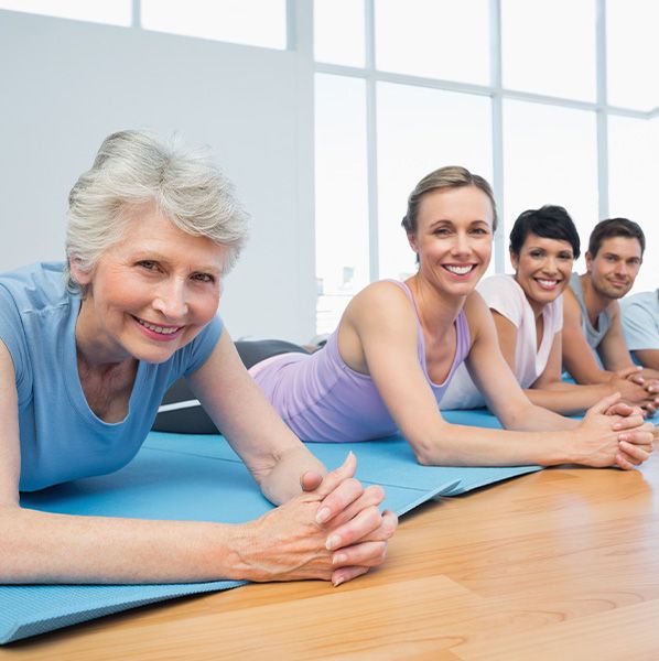 group of 4 people smiling while laying on yoga mats