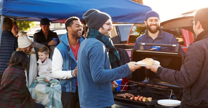 group of friends grilling at football tailgate