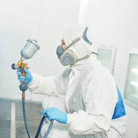 a technician in safety gear using a paint sprayer 