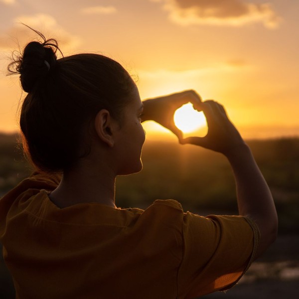 woman outdoors making shape of heart with hands