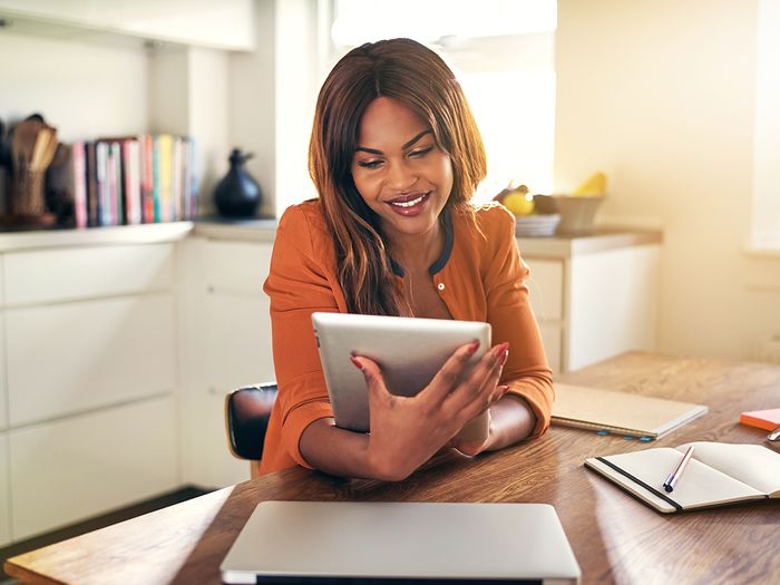 A happy woman looking at her tablet at home