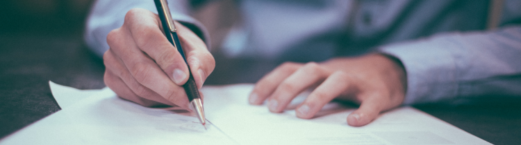 Person signing paperwork with a pen