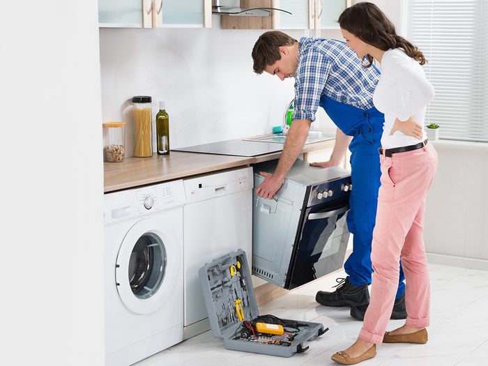 A woman watching a repairman fix an appliance