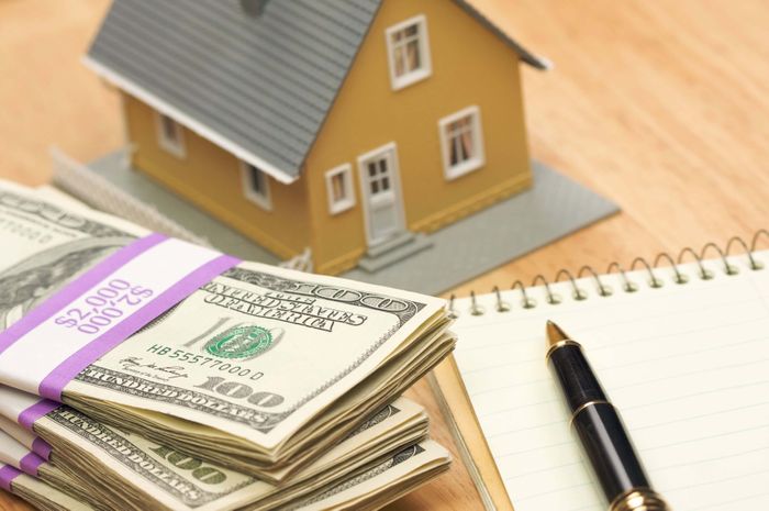 a toy house with money and a pad of paper and pen in front of it