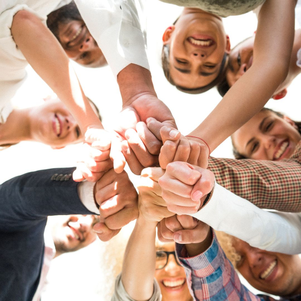 a group of various people putting their hands together