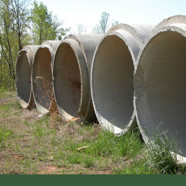 Large concrete pipes lined up in grassy area