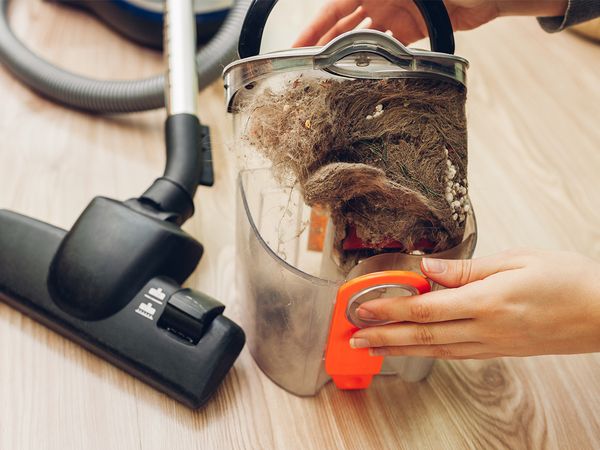 Woman emptying the canister of a vacuum cleaner