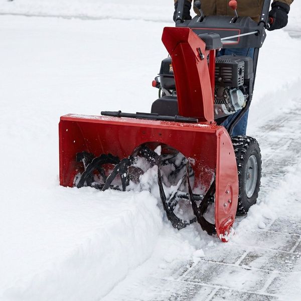 A heavy-duty commercial red snowblower in action, clearing a path through deep snow on a paved surface. A heavy-duty commercial red snowblower in action, clearing a path through deep snow on a paved surface.