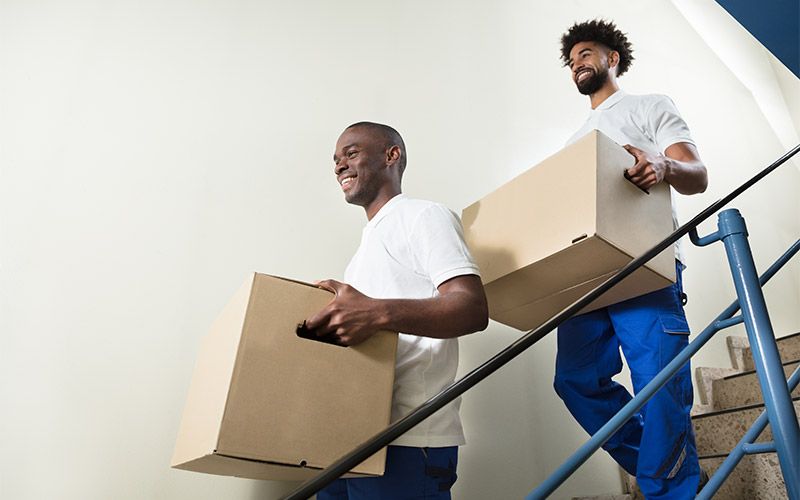 two movers walking down stairs with boxes