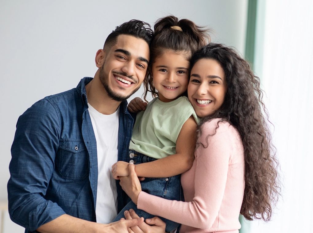 a mom, dad and daughter smile at the camera