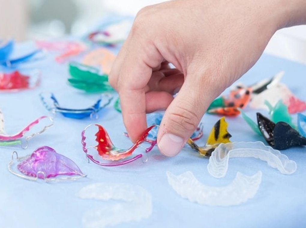a handful of retainers set on a cloth and a persons hand is reaching down to grab one a handful of retainers set on a cloth and a persons hand is reaching down to grab one