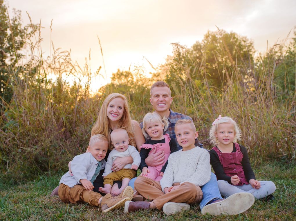 Dr. Mason with his wife and 5 kids sitting in grass posing for a picture