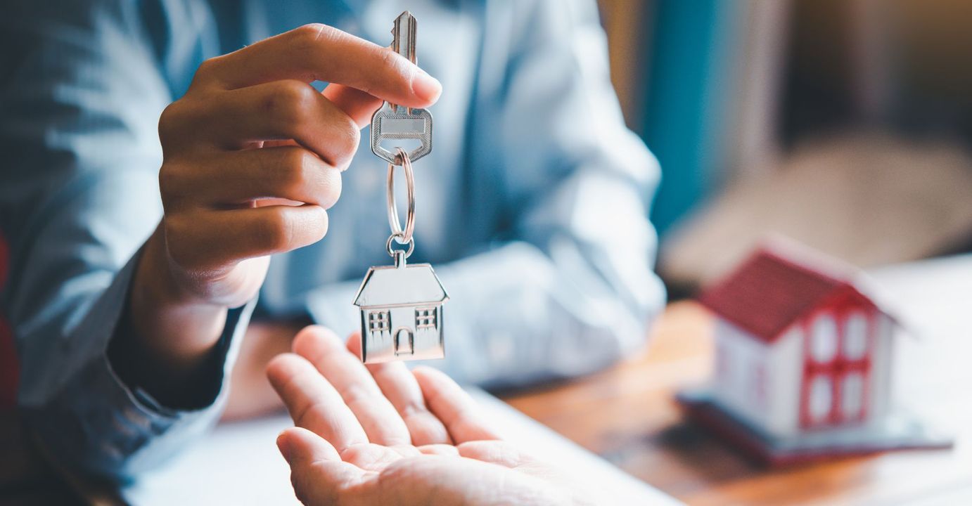 A person handing house keys to another person