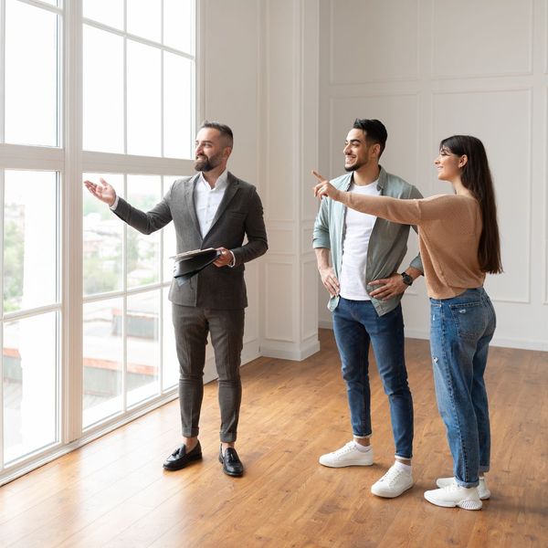 A realtor pointing out a window while speaking with two clients