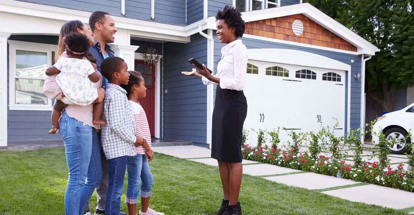 A realtor speaking with a family outside of a house