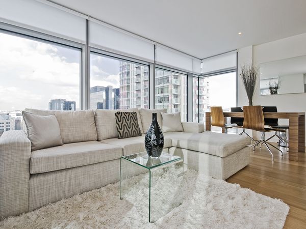 Living room with window shades on floor to ceiling windows. 