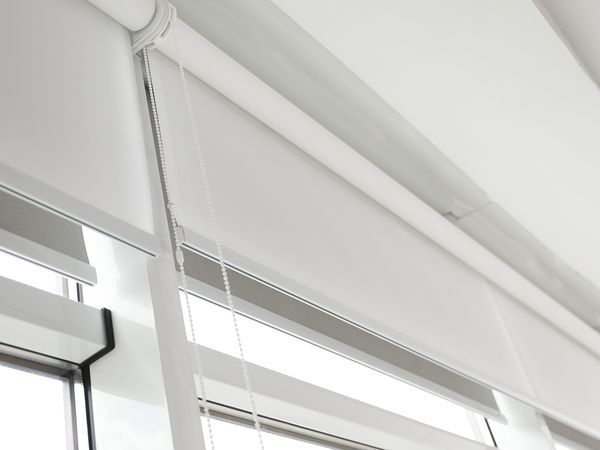 Close-up of white window shades on a roller. 