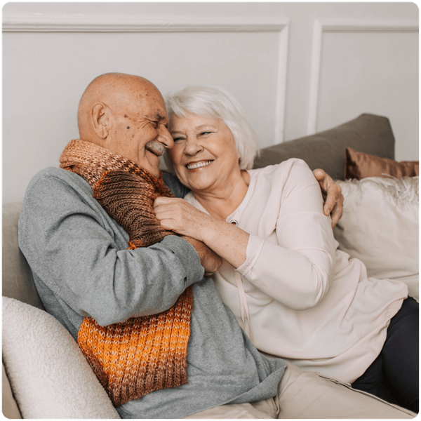 senior couple sitting on the couch together, smiling