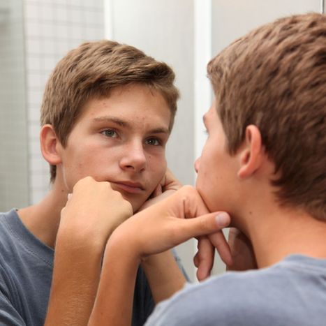 teen boy looking in mirror