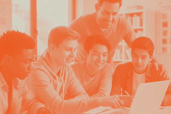 An orange-tinted photo of four teenage boys and a male mentor huddled around a laptop together in a classroom or library setting. An orange-tinted photo of four teenage boys and a male mentor huddled around a laptop together in a classroom or library setting.