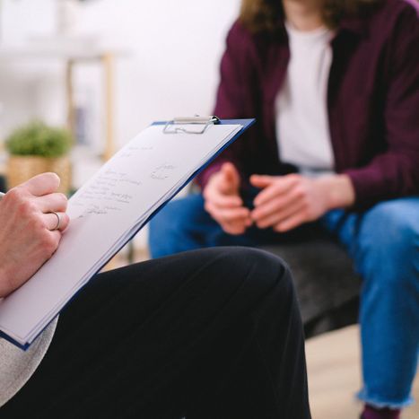 teenage boy talking to therapist taking notes
