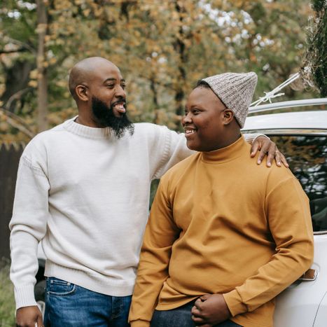 Father and son looking at eachother in front of a car Father and son looking at eachother in front of a car