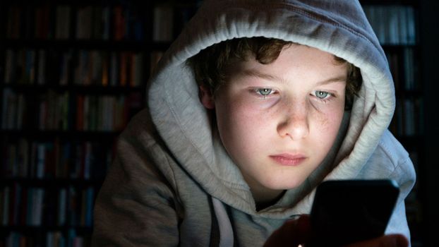 Young teen looking at phone in the dark