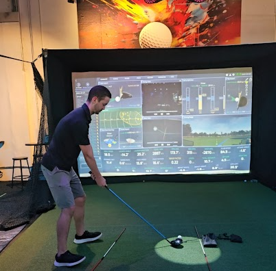 A golfer practices indoors at Warrior Golf Academy using a golf simulator and launch monitor to analyze swing data, ball flight, and performance metrics as part of Veteran and First Responder golf training. Indoor golf simulator training session at Warrior Golf Academy