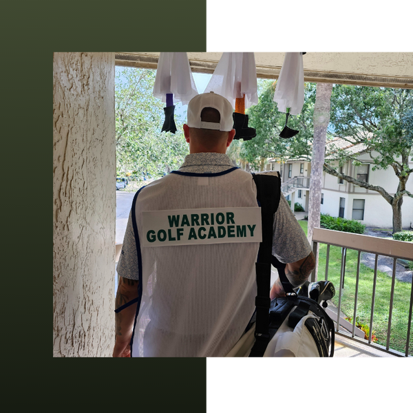 man holding golf clubs with jersey that says Warrior Golf Academy