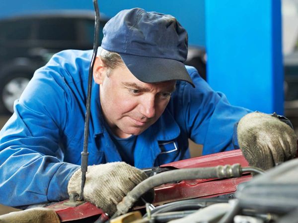 Car technician working underneath the hood of a car.