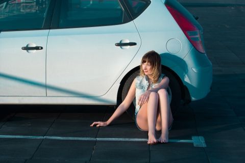image of woman leaning on her car