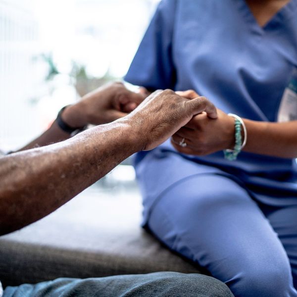 A nurse's hands holding an elderly person's hands