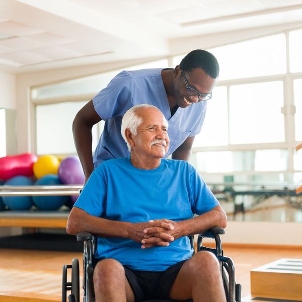 A nurse pushing a senior man out of a gym in his wheelchair