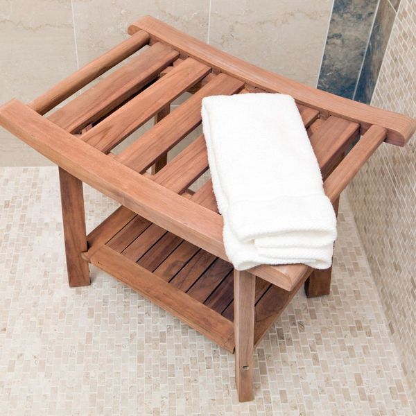 A wooden shower bench with a towel on it