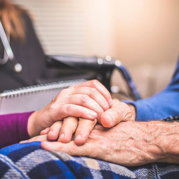 caregiver holding hands with elderly man