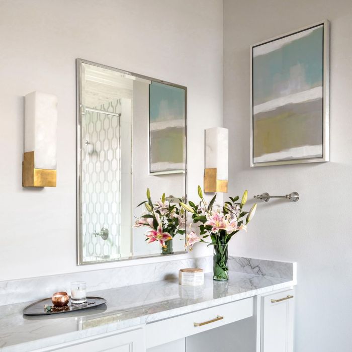 bathroom counter with a base of flowers on it