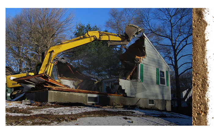 backhoe tearing down a house