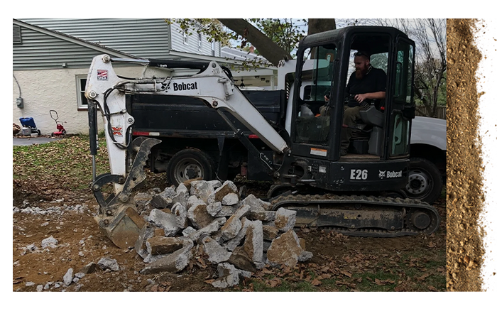 backhoe clearing out pile of broken concrete crumbles