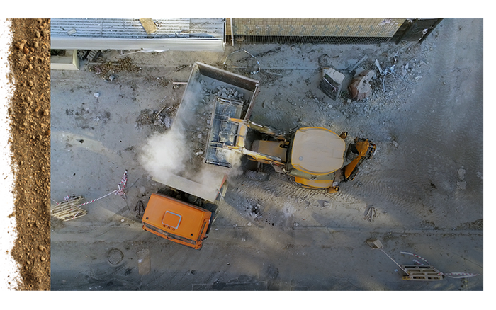 backhoe dumping material into dump truck