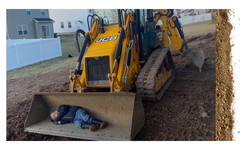 young kid laying with the bucket of a backhoe